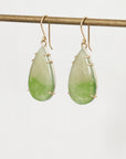 Teardrop-shaped green earrings with gold accents on a white background