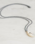 Necklace with a white pendant on a light gray background