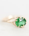 A round-cut green gemstone ring in a gold claw setting, photographed on a clean white background.