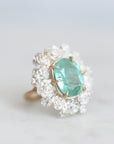 Glowing green stone held in gold prongs surrounded by silver roses