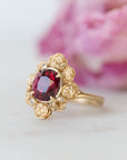 Gold ring with a red gemstone on a light background