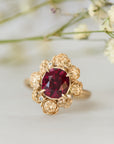 Gold ring with a red gemstone on a light background