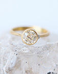 Gold ring with a diamond on a textured white surface