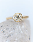 Gold ring with a diamond on a textured white surface