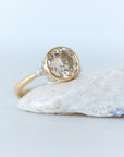 Gold ring with a large gemstone on a light blue background