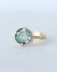 Gold ring with a green gemstone on a light gray background