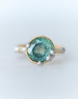Ring with a green gemstone and gold band on a light gray background
