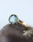 Gold ring with a green gemstone on a textured surface