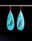 Turquoise teardrop earrings with whale design on a black background