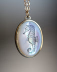Seahorse pendant on a chain against a blurred background