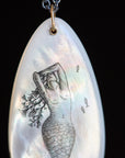 Shell pendant with mermaid illustration on a black background