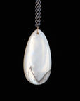 Teardrop-shaped pendant on a chain against a black background