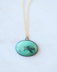 Necklace with a round pendant featuring a turtle design on a light background