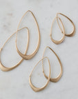three pairs of facet hoops laid out on marble, in three different sizes, in gold