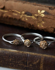 three rose sizes of silver and gold rose rings, sitting on leather books