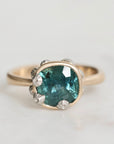 Ring with a green gemstone and gold band on a light gray background