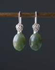 sage green jade oval beads hang beneath silver ear wires featuring little silver roses on them