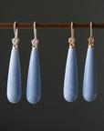 long teardrops of blue common opal hang beneath silver and gold ear wires and roses