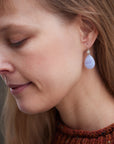 swirly pale blue lace agate teardrops hang beneath silver ear wires featuring little silver roses on them