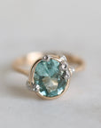 Gold ring with a green gemstone on a light gray background