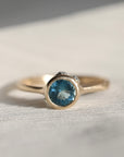 gold ring with blue stone on a pale fabric surface