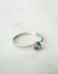 side view of blue montana sapphire stone set in a ring of platinum via prongs.