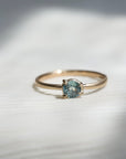 Gold ring with a light blue gemstone on a fabric background