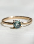 Gold ring with a light blue gemstone on a fabric background