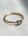 Gold ring with a light blue gemstone on a fabric background