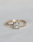 white sapphire center stone ring with diamond accents photographed against blurry grey background