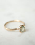 side view of round cream montana sapphire set in a ring of prongs in a gold ring