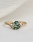 Gold ring with a green gemstone on a white fabric background