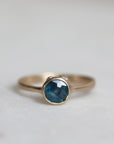 Gold ring with a blue sapphire on a light gray background