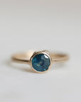 Gold ring with a blue gemstone on a light gray background