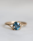 Gold ring with a blue gemstone on a light gray background