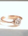 rose gold ring with diamond and three small side barnacles with diamonds- 1/4 view, in light.