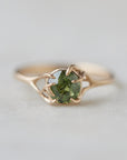 a heavily included green garnet round gemstone is set in a gold branch ring with vine-like prongs. Front view.