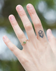 a heavily included green garnet round gemstone is set in a gold branch ring with vine-like prongs. Shown on person.