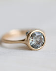 Gold ring with a gray stone on a light gray background