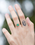 Round green emerald is set in a branch ring with branchy prongs holding the stone. Photographed on person.