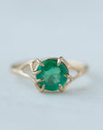 Round green emerald is set in a branch ring with branchy prongs holding the stone. Photographed on stone. Front view.