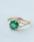 Round green emerald is set in a branch ring with branchy prongs holding the stone. Photographed on stone. 1/4 view.