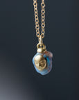 closeup of raw opal with gold face and gold chain against dark background by hannah blount