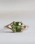 gold ring with green gemstone on pale fabric