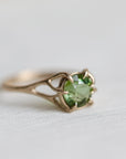 gold ring with green gemstone on pale fabric