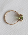 gold ring with green gemstone on pale fabric