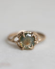 Gold ring with a multicolored gemstone on a light gray background