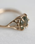 Gold ring with a multicolored gemstone on a light gray background