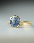 Periwinkle Montana sapphire in yellow gold bezel setting with hand-carved barnacles