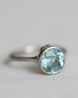 Silver ring with a light blue gemstone on a light gray background